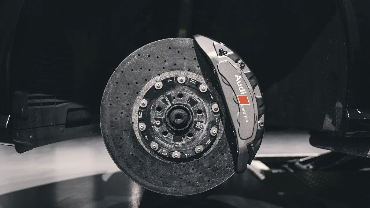 A large fixed brake caliper clamped over a drilled disc behind a wheel