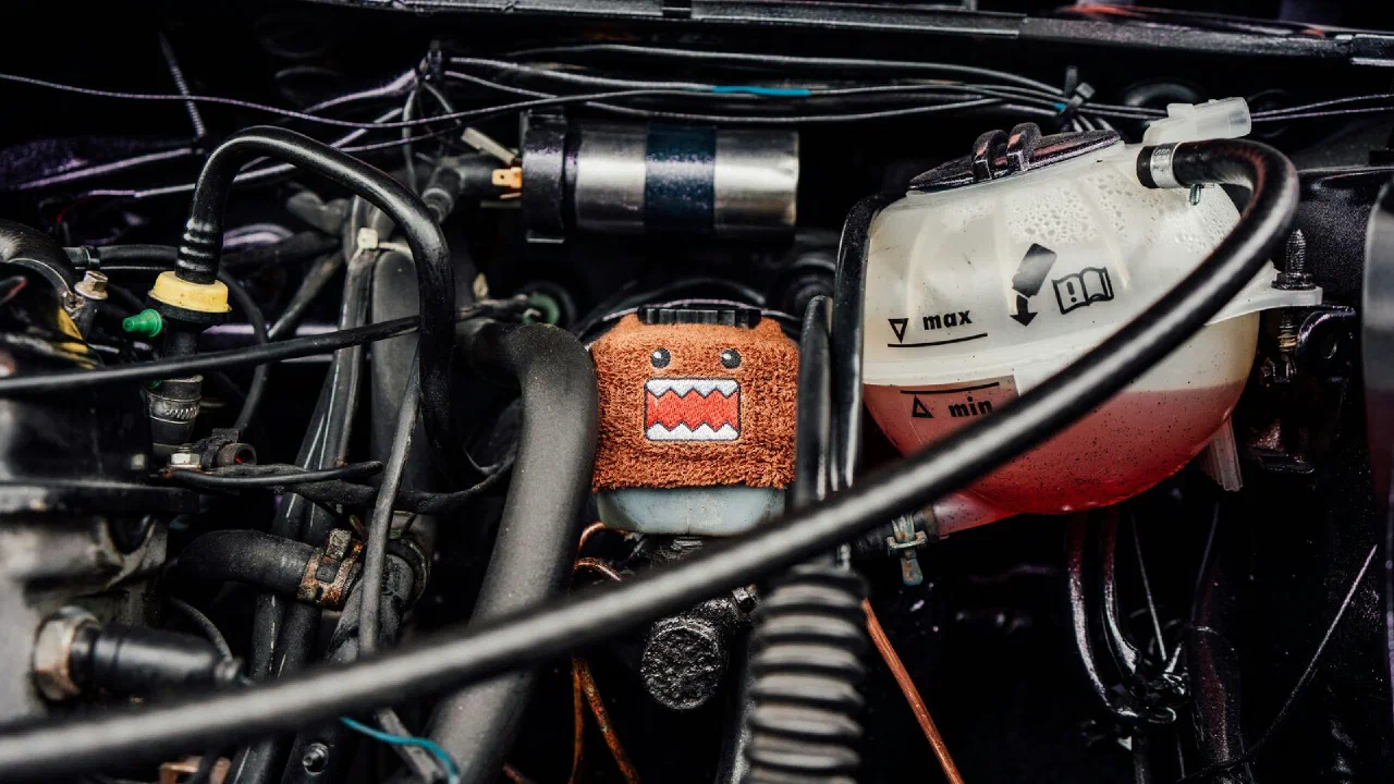 A brake fluid reservoir with a soft cover over its cap in a car engine bay